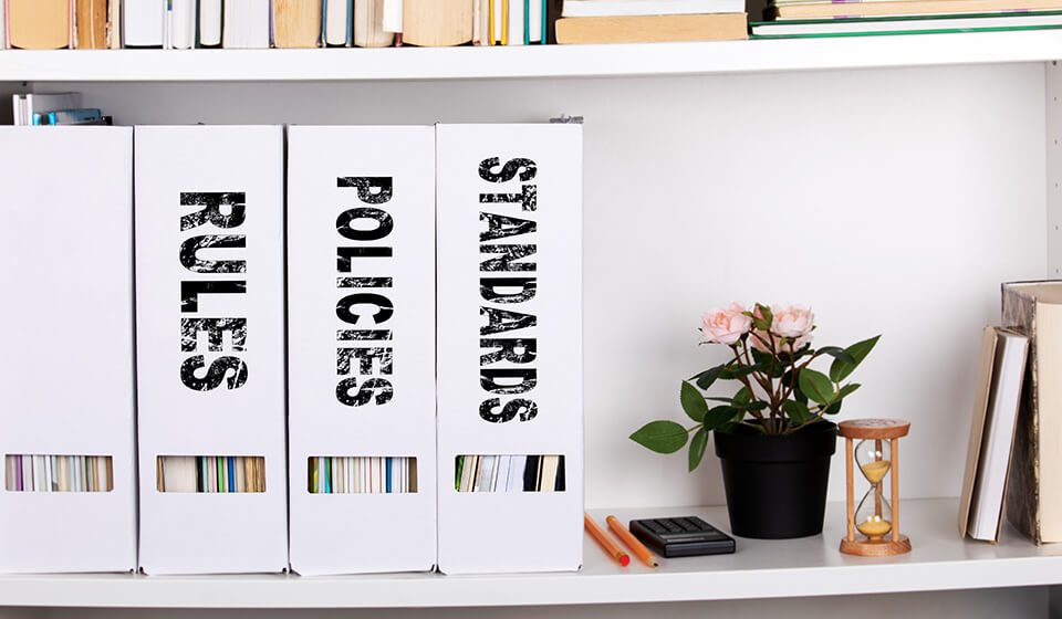 A bookshelf with three white file folders on it.